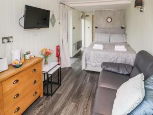een slaapkamer met een bed, een bank en een tv bij Alstroemeria in Evesham