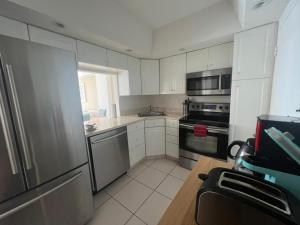 a kitchen with white cabinets and a stainless steel refrigerator at Entire Beach Front Condo w/ pool Amazing view 4pax in Miami Beach