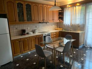 uma cozinha com armários de madeira, uma mesa de vidro e cadeiras em Argostoli Apartment em Argostoli