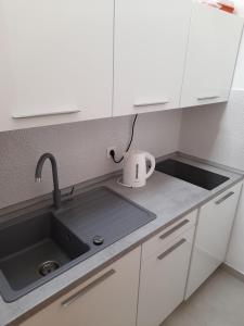 una cocina con armarios blancos y fregadero en Apartments Marnic, en Mlini