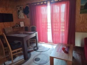 uma sala de estar com uma mesa e cortinas vermelhas em Vila Suza em Jezdići