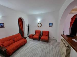 uma sala de estar com duas cadeiras vermelhas e um sofá em Ischia Villa Casa Caruso con piscina 6 posti letto em Ischia