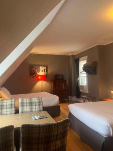 a hotel room with two beds and a table and chairs at E-Hotel Des Grisons - Par Aneyro in Quebec City