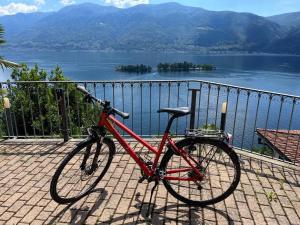 uma bicicleta vermelha estacionada ao lado de uma cerca com um lago em Idyllic studio with panoramic views em Ronco sopra Ascona