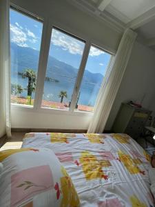 um quarto com uma cama e uma grande janela em Idyllic studio with panoramic views em Ronco sopra Ascona