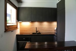 cocina con armarios negros, fregadero y ventana en Apartment EigerView, en Grindelwald