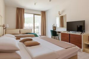 a hotel room with a bed and a desk and a television at Hotel Kadmo by Aycon in Budva