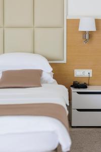 1 dormitorio con 1 cama y mesita de noche con lámpara en Hotel Kadmo by Aycon en Budva