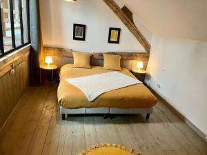 a bedroom with a bed with two tables and two lamps at Le Grenier d'Ouilly au cœur du Pays d'Auge - Gîte avec piscine à 20 min des plages in Ouilly-le-Vicomte