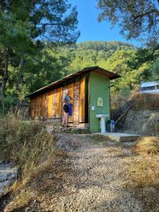 a person standing in front of a small building at Sultaniye Camping in Mugla