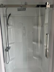 a shower stall with a glass door with shelves at Les chambres des Grisons établissement sans contact in Quebec City