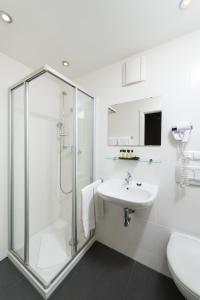 baño blanco con ducha y lavamanos en Hotel Munich Inn - Design Hotel en Múnich
