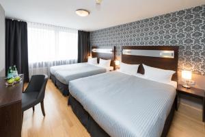 a hotel room with two beds and two lamps at Hotel Munich Inn - Design Hotel in Munich