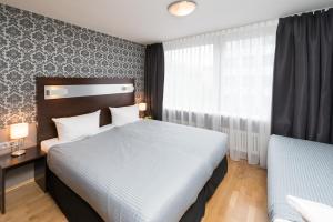 a hotel room with a large bed and a large window at Hotel Munich Inn - Design Hotel in Munich