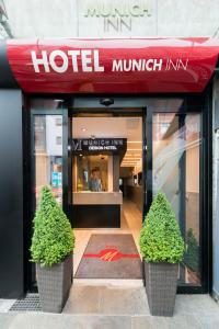 a hotel entrance with two plants in front of it at Hotel Munich Inn - Design Hotel in Munich