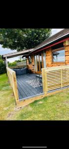 a large wooden deck in front of a house at Angies Den - quirky cabin with hot tub & views in Llanasa