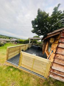 a large wooden deck next to a house at Angies Den - quirky cabin with hot tub & views in Llanasa