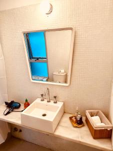 La salle de bains est pourvue d'un lavabo blanc et d'un miroir. dans l'établissement PALERMO HOLLYWOOD loft, à Buenos Aires