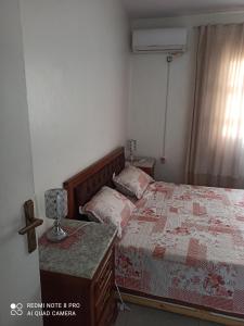 een slaapkamer met een bed en een tafel met een lamp bij Ain Naadja Gue De Constantine 