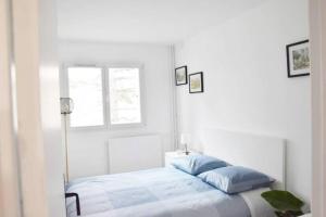 een witte slaapkamer met een bed en een raam bij Appartement 4 Chambres in Champigny-sur-Marne