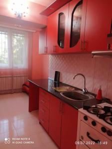 a red kitchen with a sink and a stove at Cozy apartment in Sevan City in Sevan