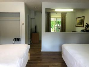 Habitación con 2 camas y espejo. en Bavarian Orchard Motel, en Creston
