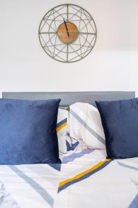 a bed with blue pillows and a clock on the wall at Modern Studios with Ensuite, Separate Kitchen, and Prime Location in St Helen Apt 2 in Saint Helens