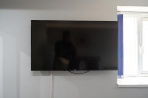 TV de pantalla plana colgada en la pared en Modern Studios with Ensuite, Separate Kitchen, and Prime Location in St Helen Apt 2, en Saint Helens