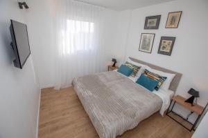 een witte slaapkamer met een bed met blauwe kussens bij Somptueux deux pièces vue mer + parking in Beausoleil