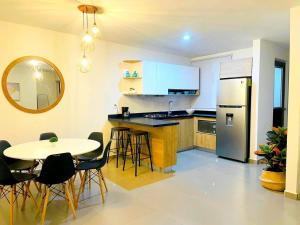 cocina con mesa, nevera, mesa y sillas en Excelente Departamento con Alberca cerca de Playa - Residencial Coto Mareta I, en Mazatlán