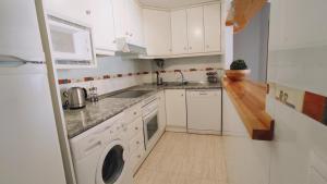 a white kitchen with a sink and a dishwasher at Heydays Apartment in La Mata