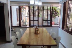 a wooden table with white chairs in a room with windows at Ayenda Casa 12 in Santa Marta