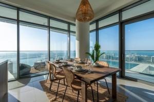 a dining room with a table and chairs and large windows at Luxury Penthouse I 220 deg View of the Palm I Dubai Harbour I Private Beach in Dubai