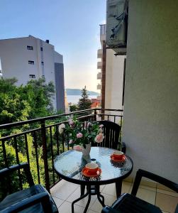 a table with two cups and flowers on a balcony at A step to the sea-Na korak do mora-Studio apartments Bela kuća in Rafailovici