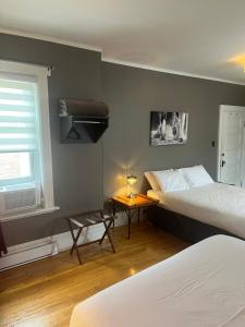 sypialnia z 2 łóżkami, stołem i oknem w obiekcie Les chambres des Grisons établissement sans contact w mieście Quebec City