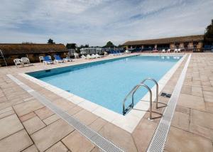 a large swimming pool with blue water and chairs at Holiday home / Caravan in Felpham