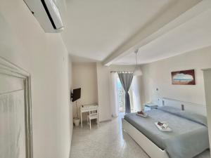 Habitación blanca con cama y escritorio en Il Nido delle Rondini, en Formia