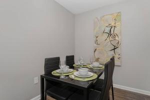 a dining room table with black chairs and plates and a painting at King Beds 2- Smart TVs-Free Parking-Patio in Greensboro