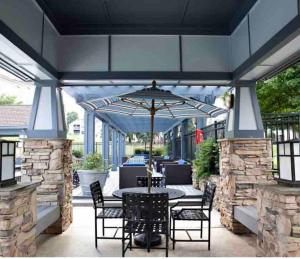 King Beds 2- Smart TVs-Free Parking-Patio في جرينسبورو: فناء مع طاولة وكراسي ومظلة