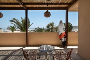 Prasonisi Light House Boutique Hotel في براسونيسي: لوح ركوب الأمواج على شرفة مع طاولة وكراسي