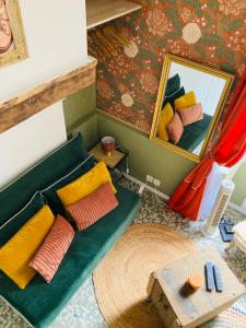 een woonkamer met een groene bank en een spiegel bij L’Hortense in Oloron-Sainte-Marie