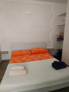 un lit blanc avec des draps et des serviettes orange dessus dans l'établissement Emanuela Apartments 1.0, à Torre Santa Sabina
