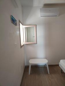 Cette chambre blanche dispose d'une table et d'une fenêtre. dans l'établissement Emanuela Apartments 1.0, à Torre Santa Sabina