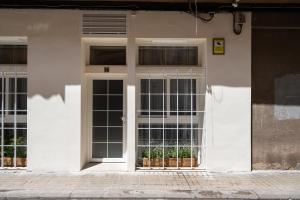 - un bâtiment blanc avec des fenêtres et une porte dans l'établissement Apartamento Boutique estilo Provenzal, El Grao Valencia, à Valence