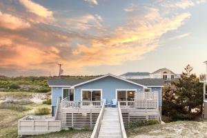 Casa azul en la playa con muelle de madera en Bear Inn, en Knotts Island