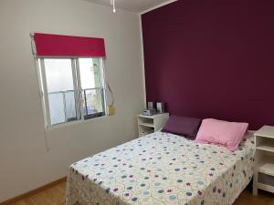 a bedroom with a bed with purple walls and a window at Mercado y playa in Isla Cristina