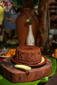 a chocolate cake on a wooden cutting board with a knife at Indaiá Eco Village in Ilhéus