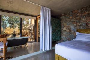 a bedroom with a bed and a bath tub next to a window at Muar Suites in Agios Pavlos