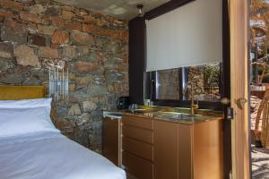 1 dormitorio con lavamanos y pared de piedra en Muar Suites, en Agios Pavlos