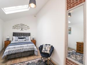 a bedroom with a bed and a mirror and a chair at The Stables in Worcester